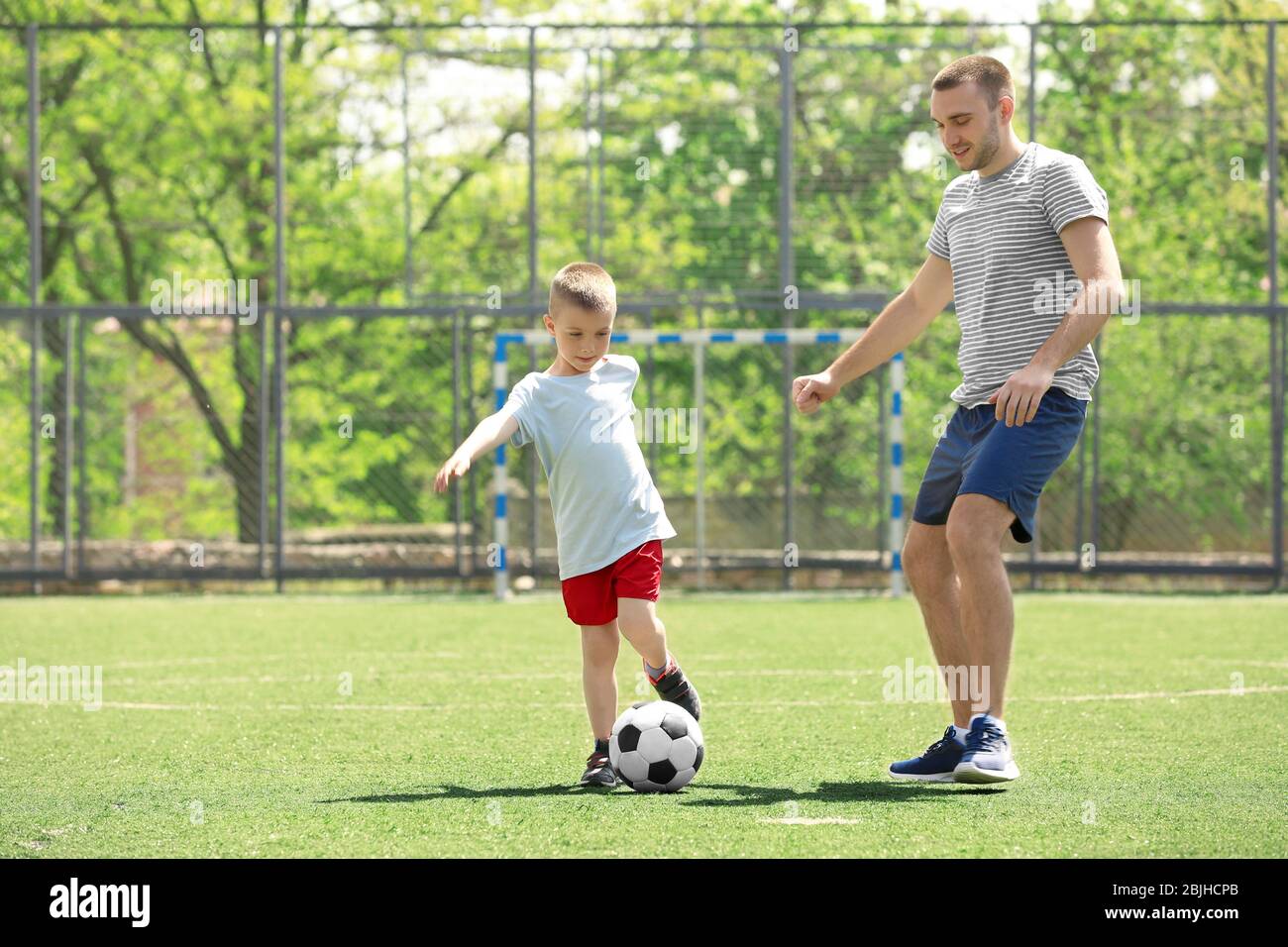 Father and son playing football on soccer pitch Stock Photo Alamy
