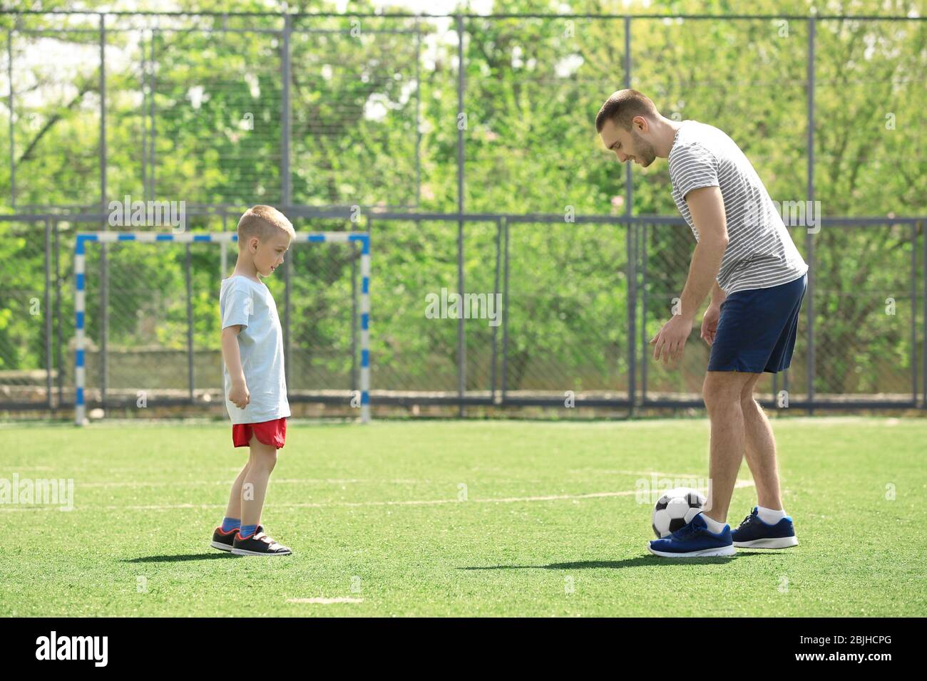 Father and son playing football on soccer pitch Stock Photo Alamy