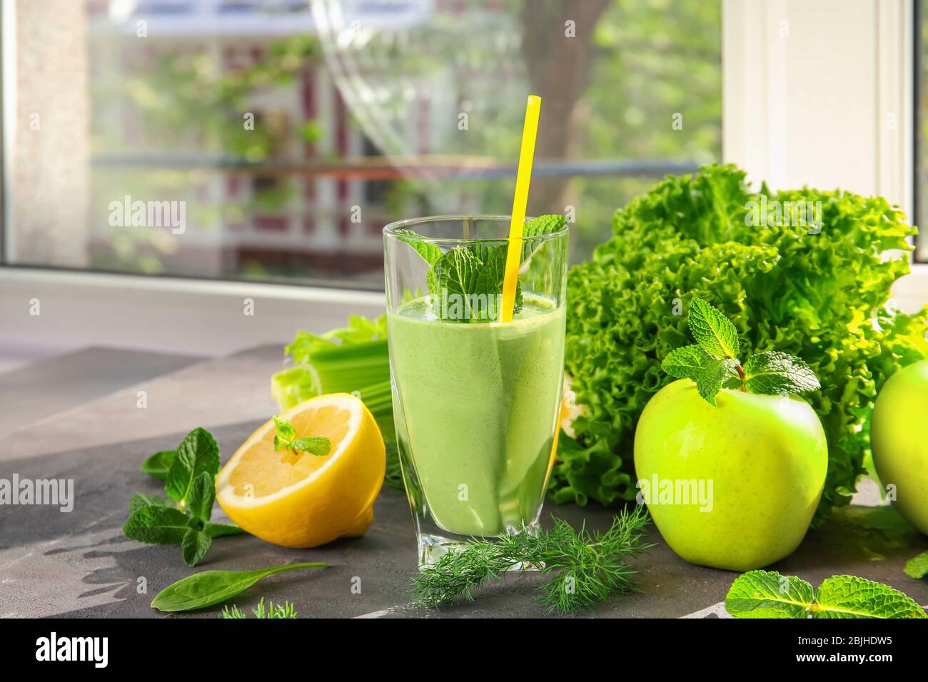Glass of green healthy juice with fruits and vegetables on table Stock ...