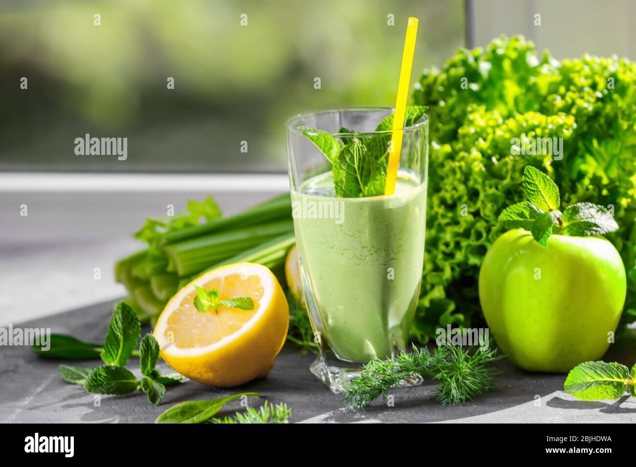 Glass of green healthy juice with fruits and vegetables on table Stock ...