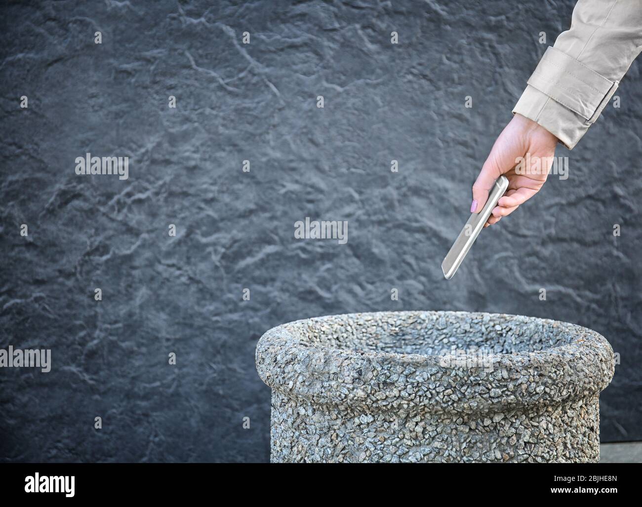 Woman throwing phone into stone bin on street Stock Photo Alamy