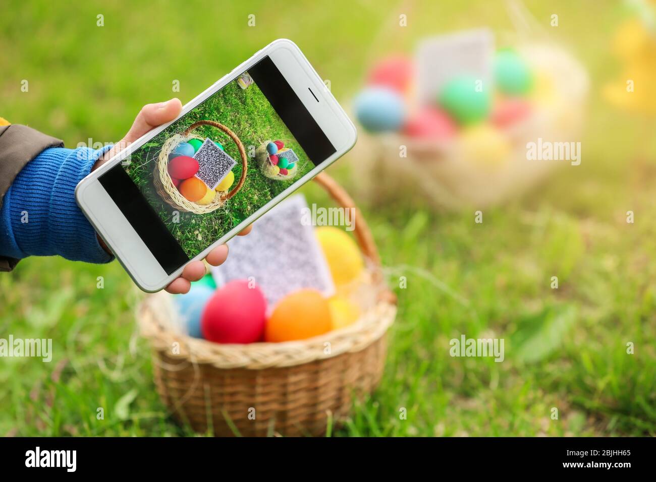 Little boy scanning QR Code in basket with colorful eggs at park