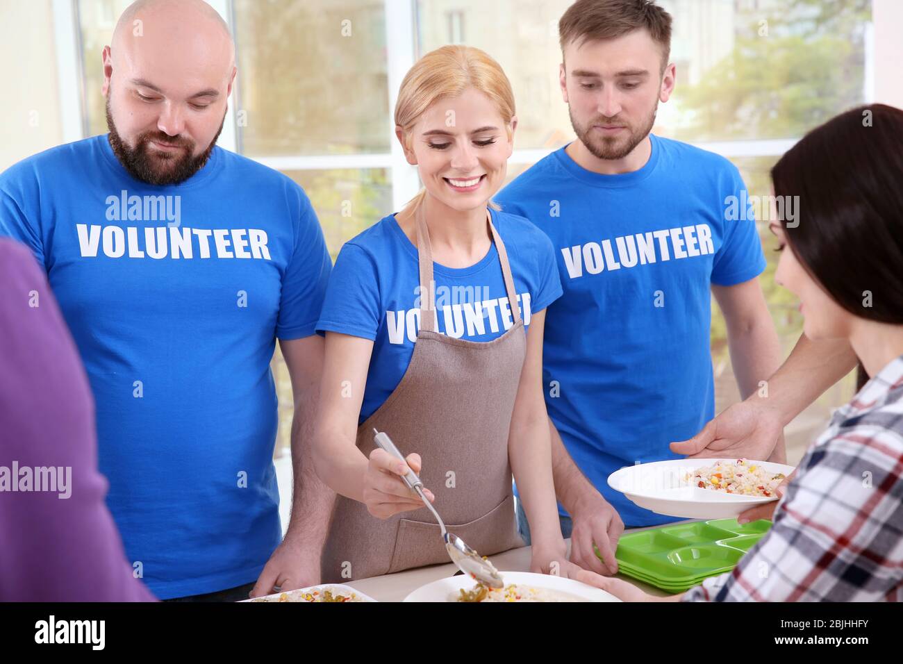 Young volunteers serving food to homeless people Stock Photo - Alamy