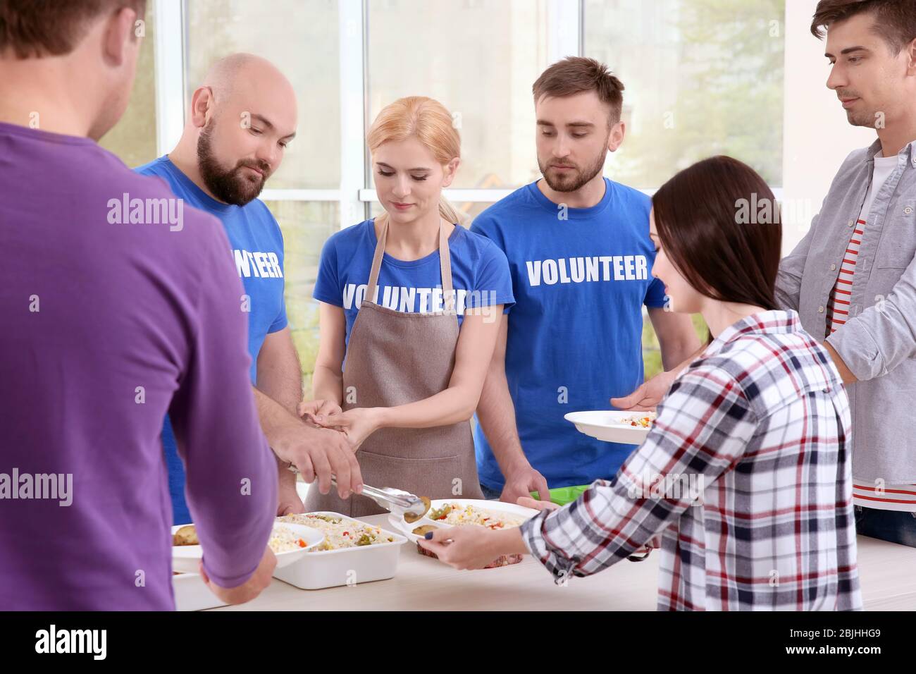 Young volunteers serving food to homeless people Stock Photo - Alamy