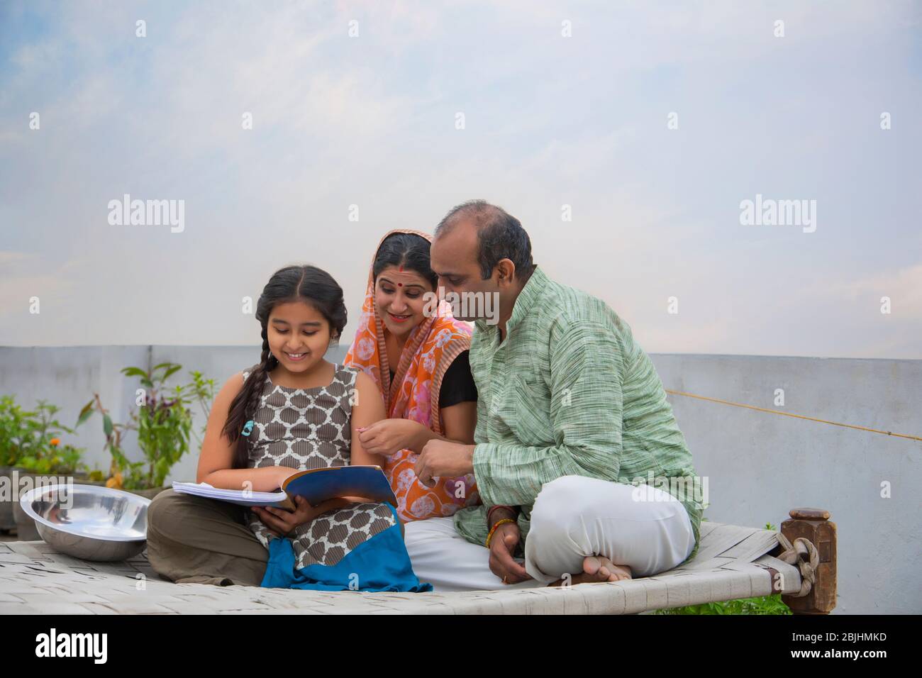 Indian mother and father helping daughters with homework Stock Photo