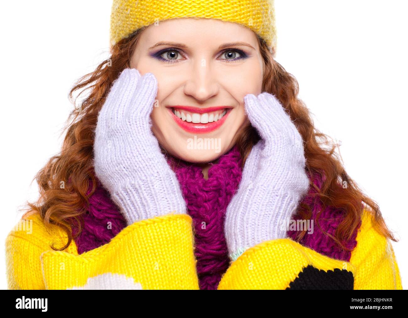 Young woman in winter clothes on a white background with hands near face Stock Photo