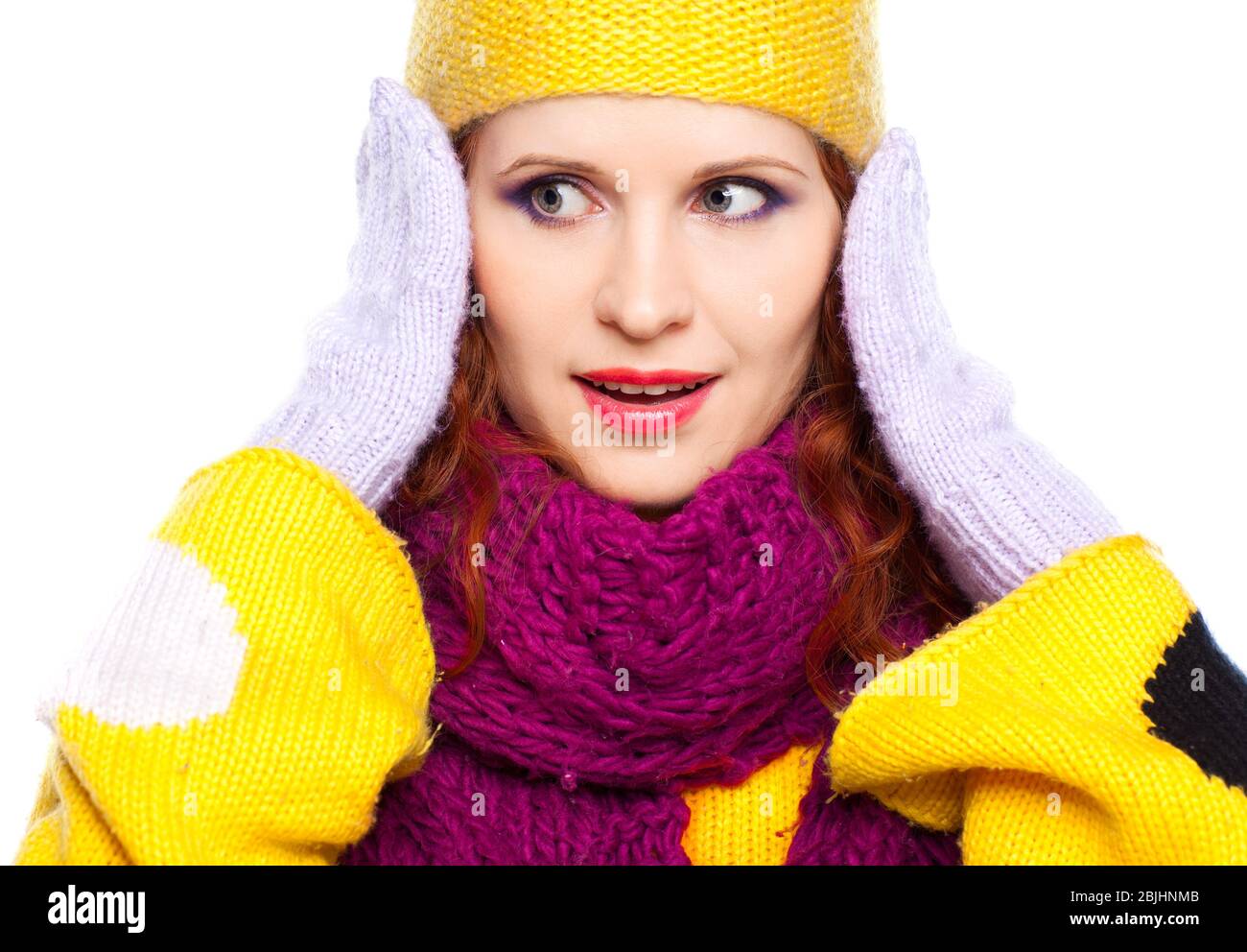 Young woman in winter clothes on a white background with hands near face Stock Photo