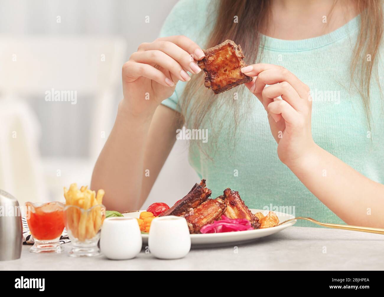 Young woman eating delicious ribs for lunch in restaurant Stock Photo Alamy