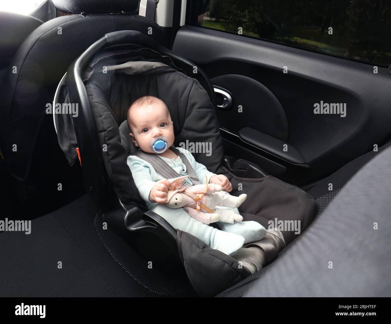 Cute baby boy with pacifier sitting in safety car seat Stock Photo Alamy
