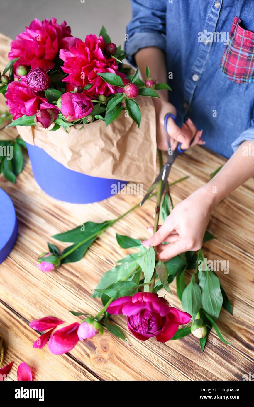 Female florist making bouquet of beautiful peonies in flower shop Stock ...