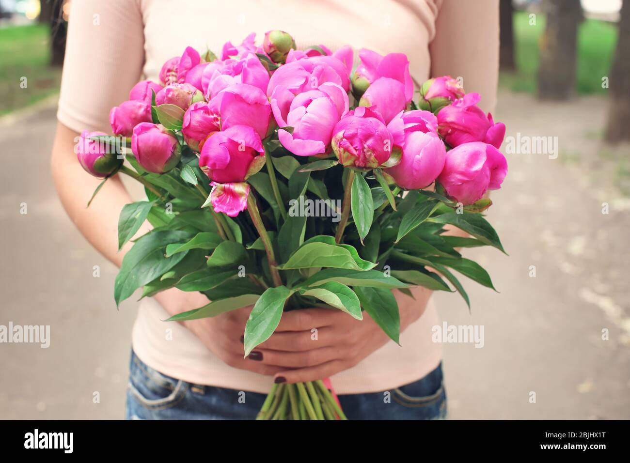 Young woman holding bouquet with beautiful peonies on street Stock ...