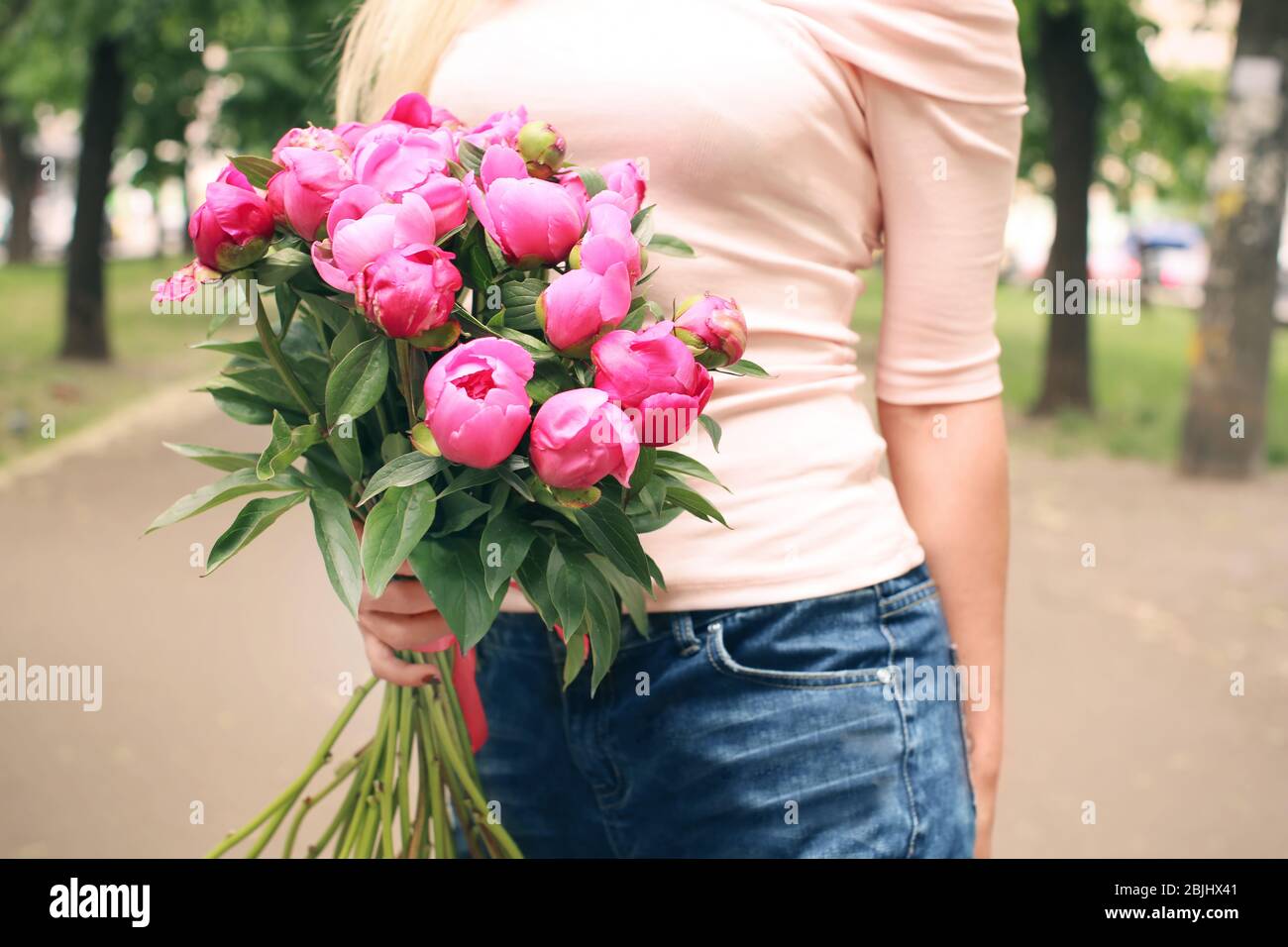 Young woman holding bouquet with beautiful peonies on street Stock ...