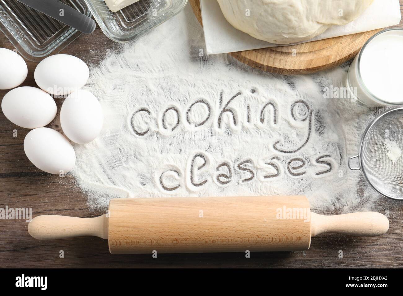 Text written on flour and ingredients, wooden background. Cooking ...