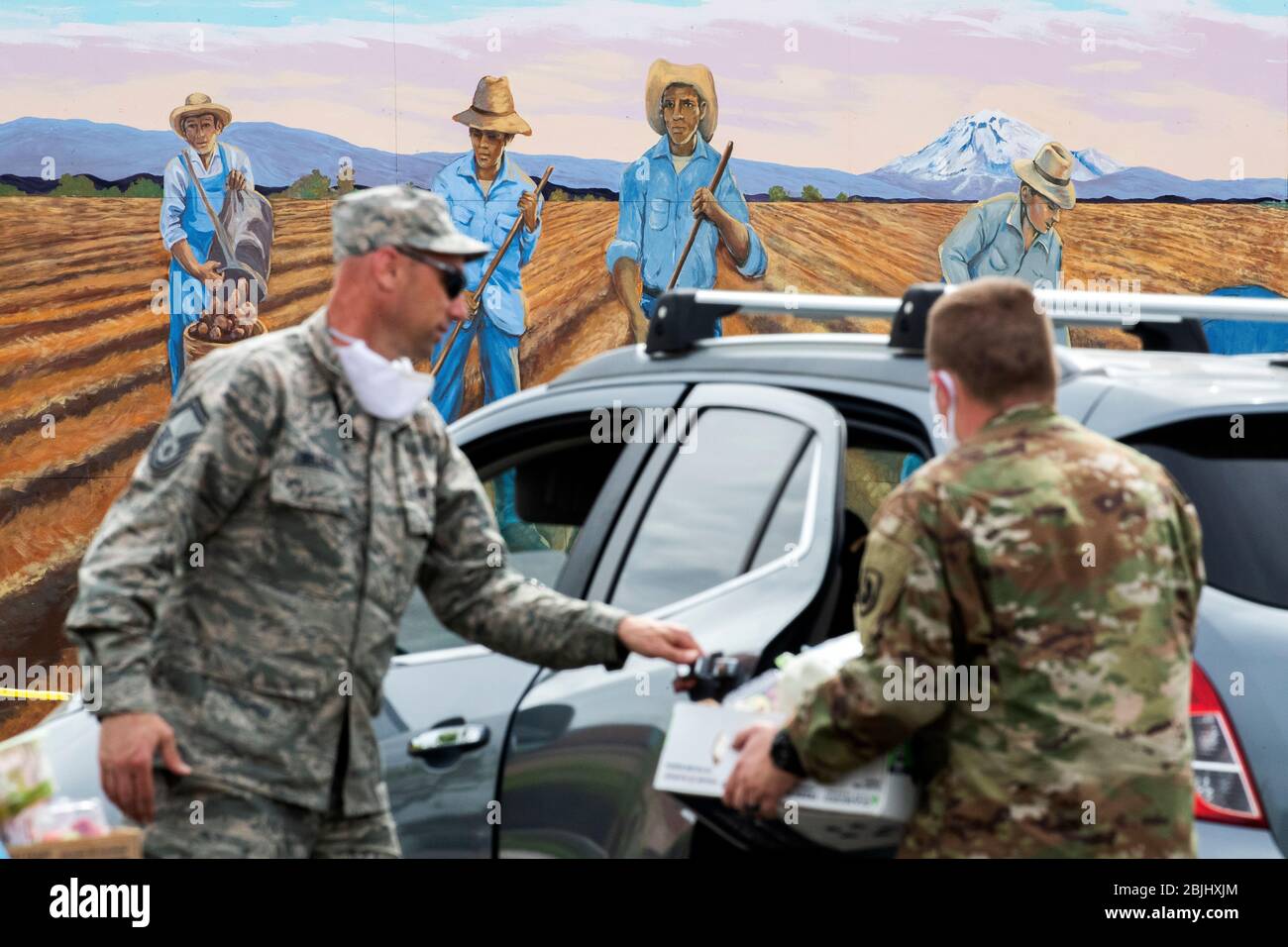 A mural depicting farmworkers is seen as Washington National Guard soldiers distribute boxes of free food to residents under state-imposed stay-at-hom Stock Photo