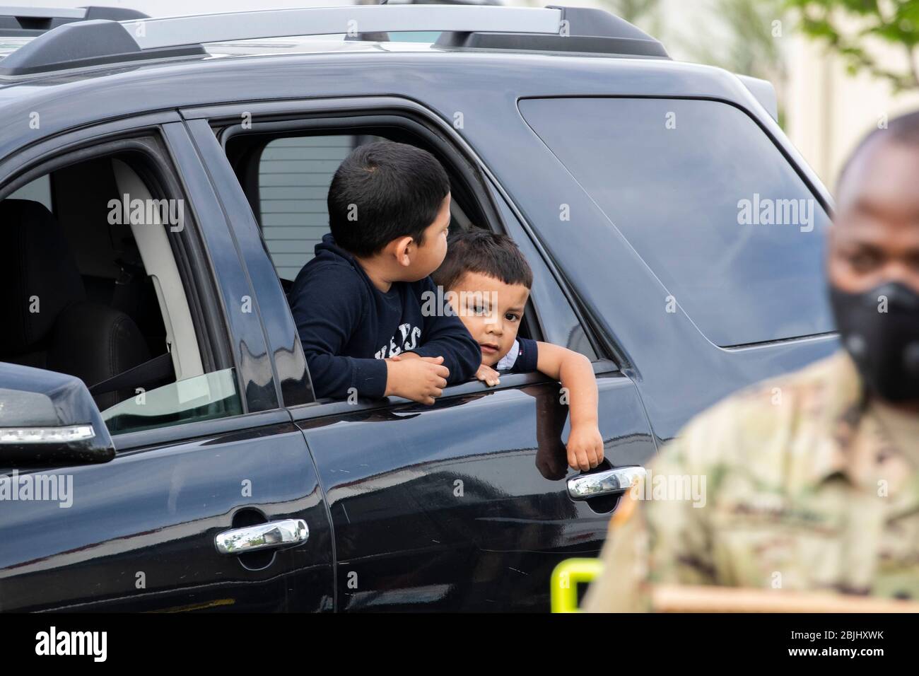 Josue Moreno (R) and his brother, Javier, wait to pick up free food with their family as Washington National Guard soldiers distribute food to residen Stock Photo