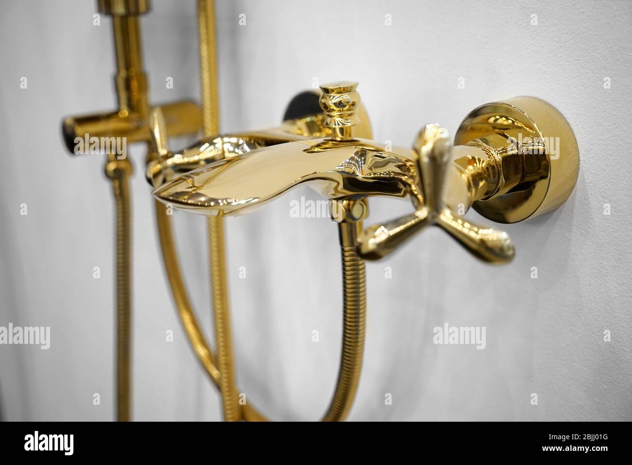 New golden shower faucet on wall, closeup Stock Photo - Alamy