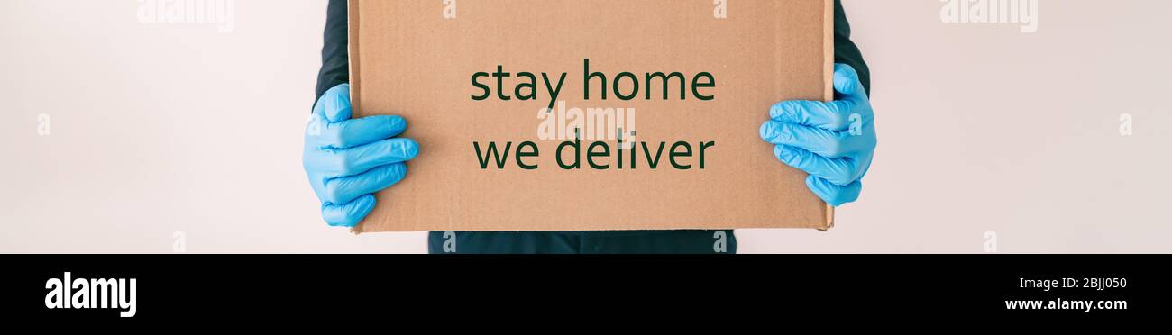 Home delivery with quote STAY HOME WE DELIVER on cardboard box banner. Food grocery delivered with gloves for COVID-19 quarantine from coronavirus social distancing. man giving purchase. Stock Photo