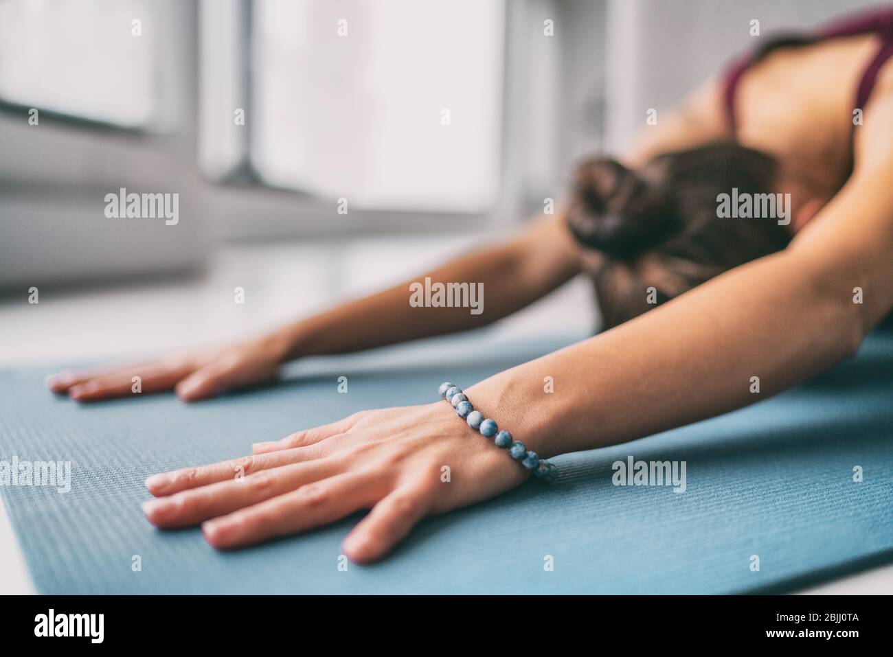 Yoga meditation wellness background - woman doing childs pose stretch on exercise mat - training fitness class at home or gym active living. Stock Photo