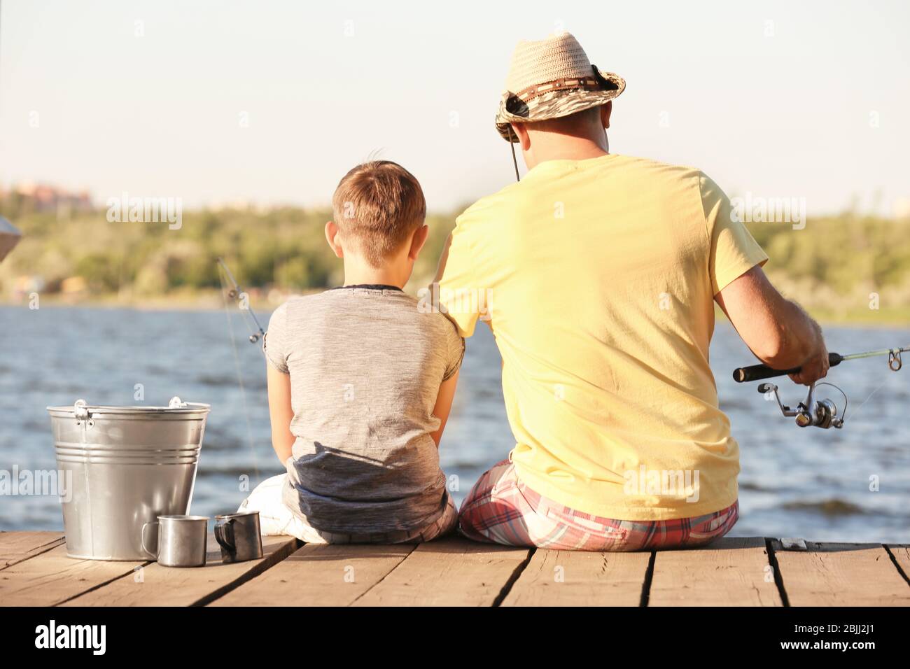 Dad and son fishing from pier on river Stock Photo - Alamy