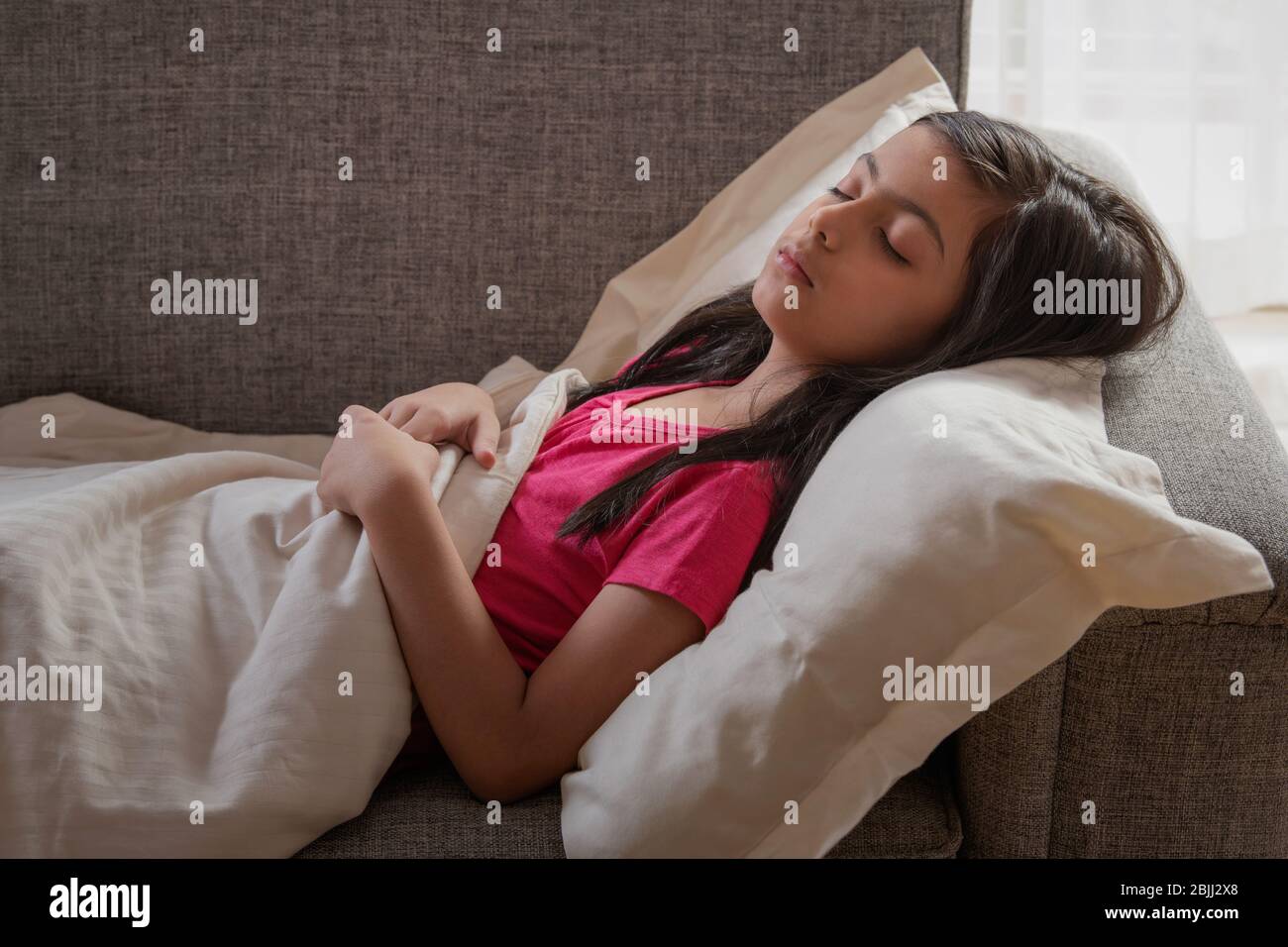 Young girl sleeping peacefully on the couch at home. (Children Stock