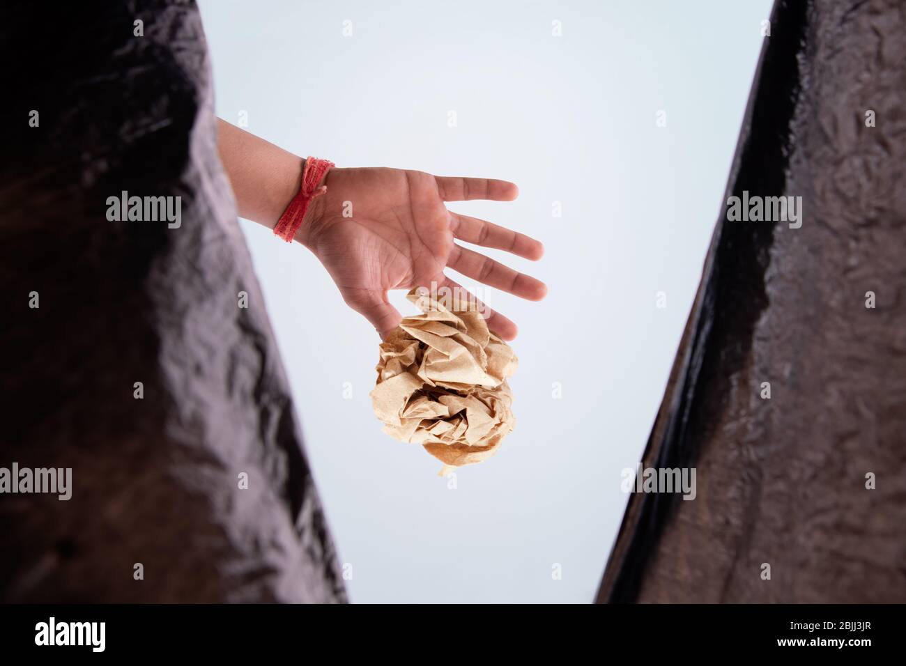 Person throwing waste inside a garbage bag. (Children) Stock Photo