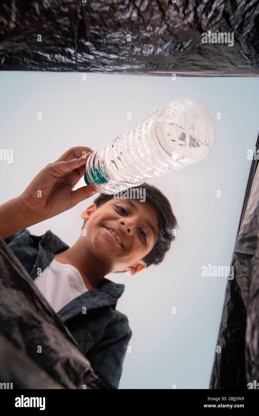 Young boy throwing waste in a garbage bag. (Children) Stock Photo