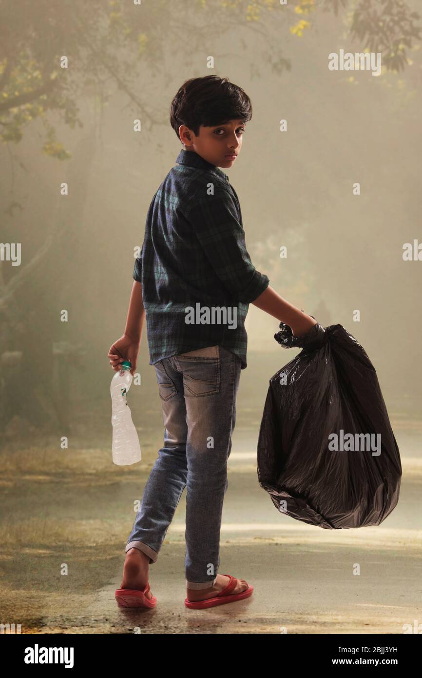 Young boy collecting garbage from the streets and helping the environment. (Children) Stock Photo