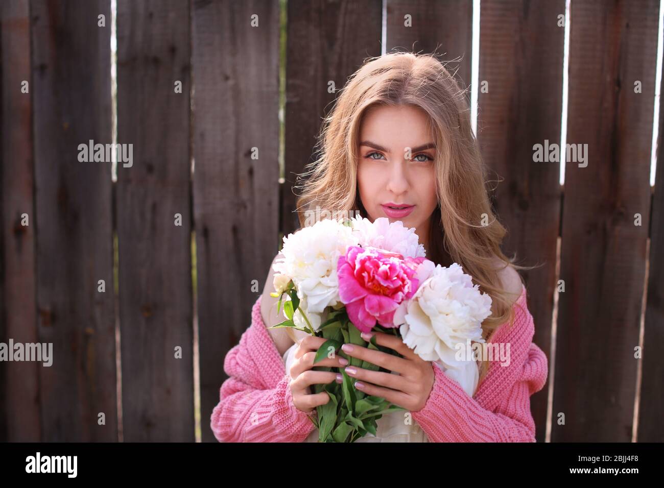 Beautiful young woman with bouquet of peonies near wooden fence Stock ...