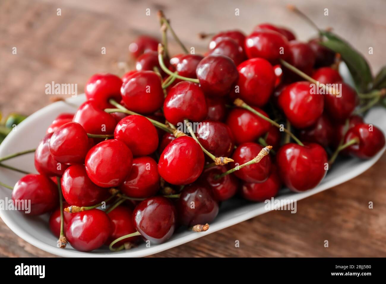Plate with fresh ripe cherries on wooden table Stock Photo - Alamy