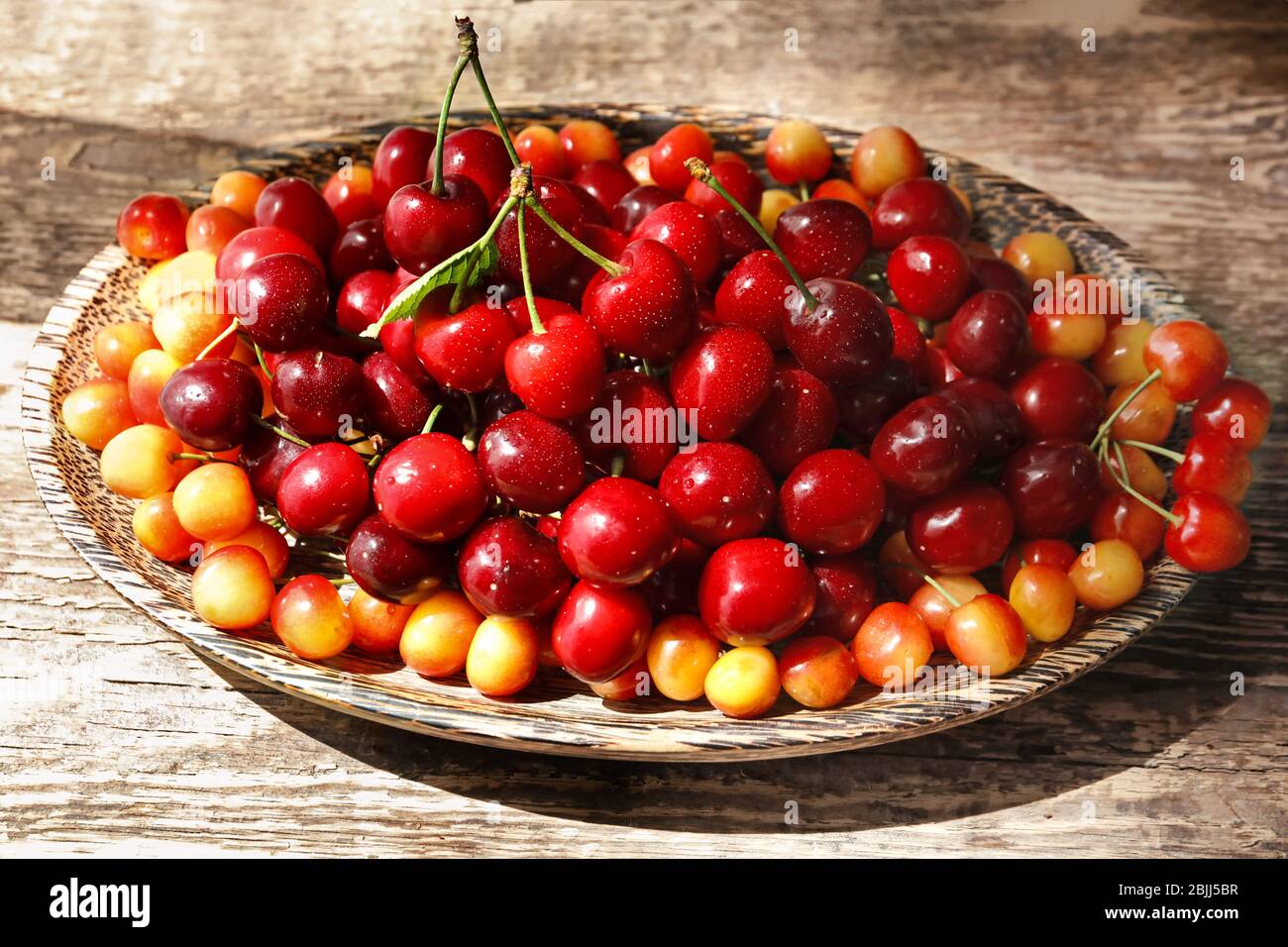 Plate with fresh ripe cherries on wooden table Stock Photo - Alamy