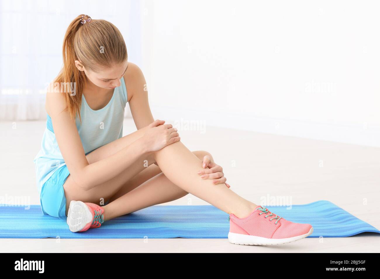 Young woman suffering from pain in leg at home Stock Photo - Alamy