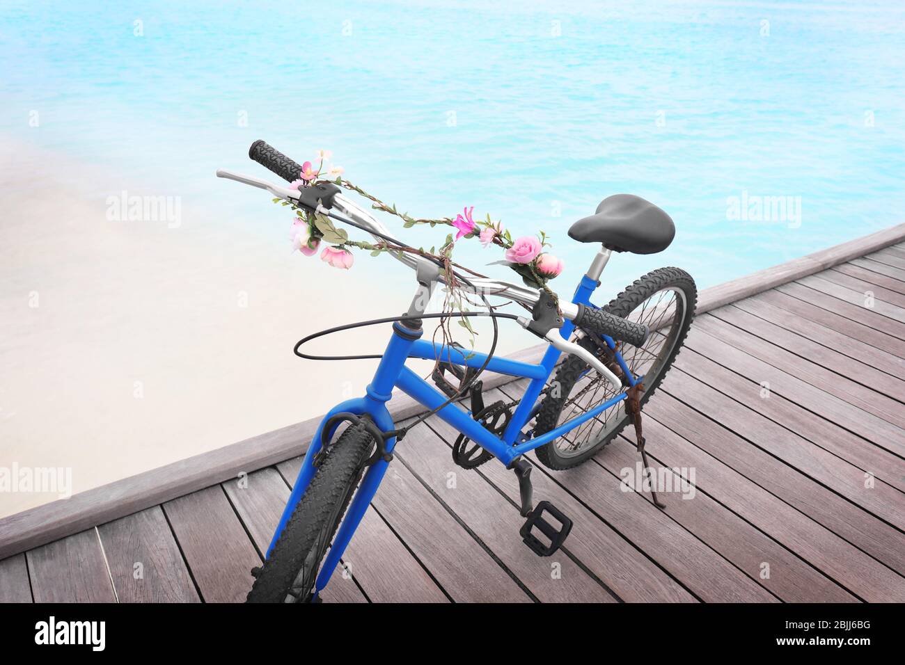 Modern bicycle with flower garland on sea beach Stock Photo Alamy
