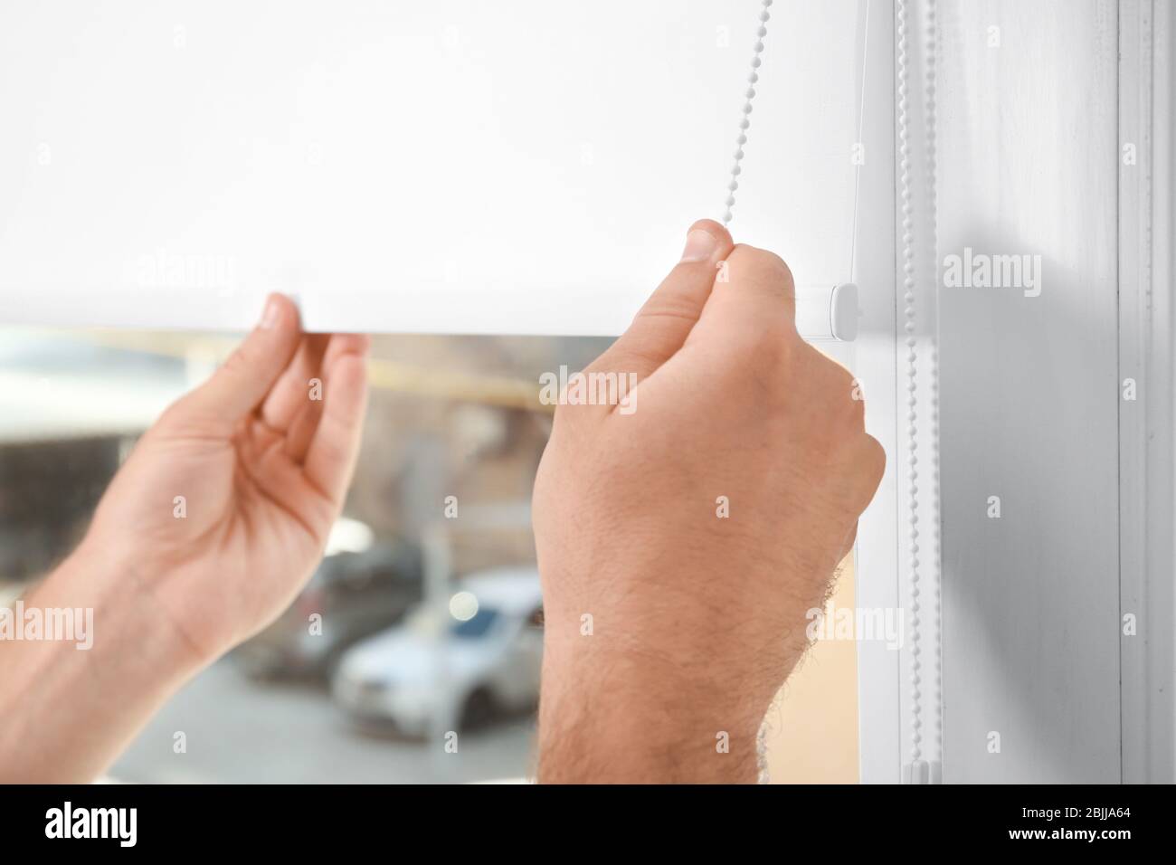 Young man installing window screens indoors Stock Photo