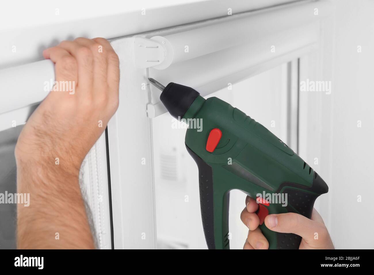 Young man installing window screens indoors Stock Photo
