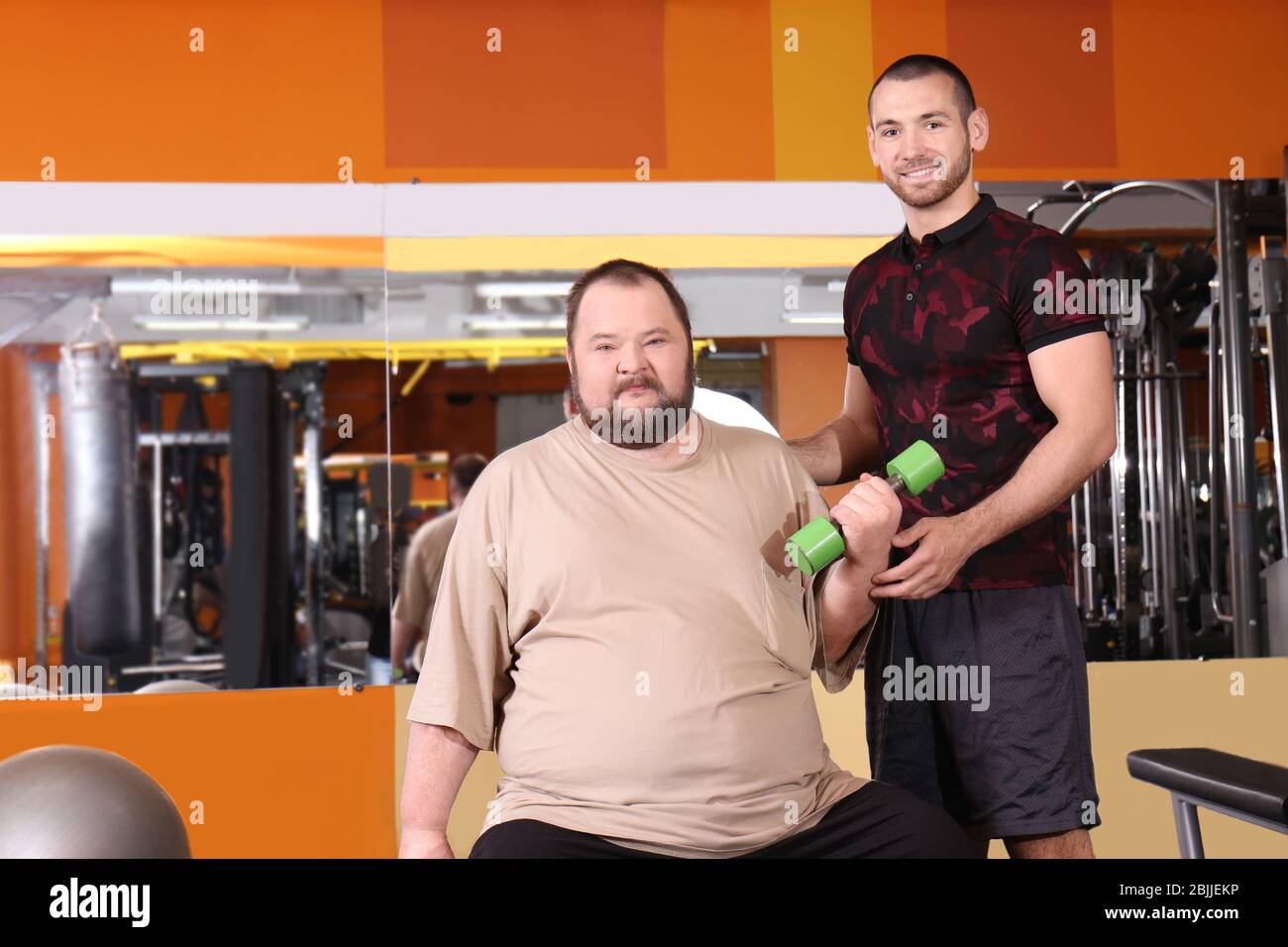 Overweight man with trainer in gym Stock Photo - Alamy