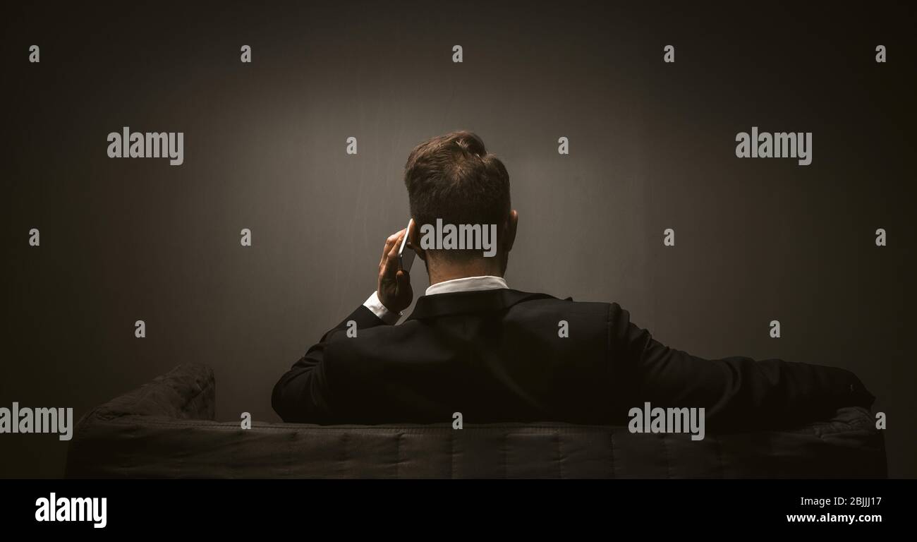 Modern business person on dark backdrop. Mobile phone wireless communication concept. Mobile communications Stock Photo