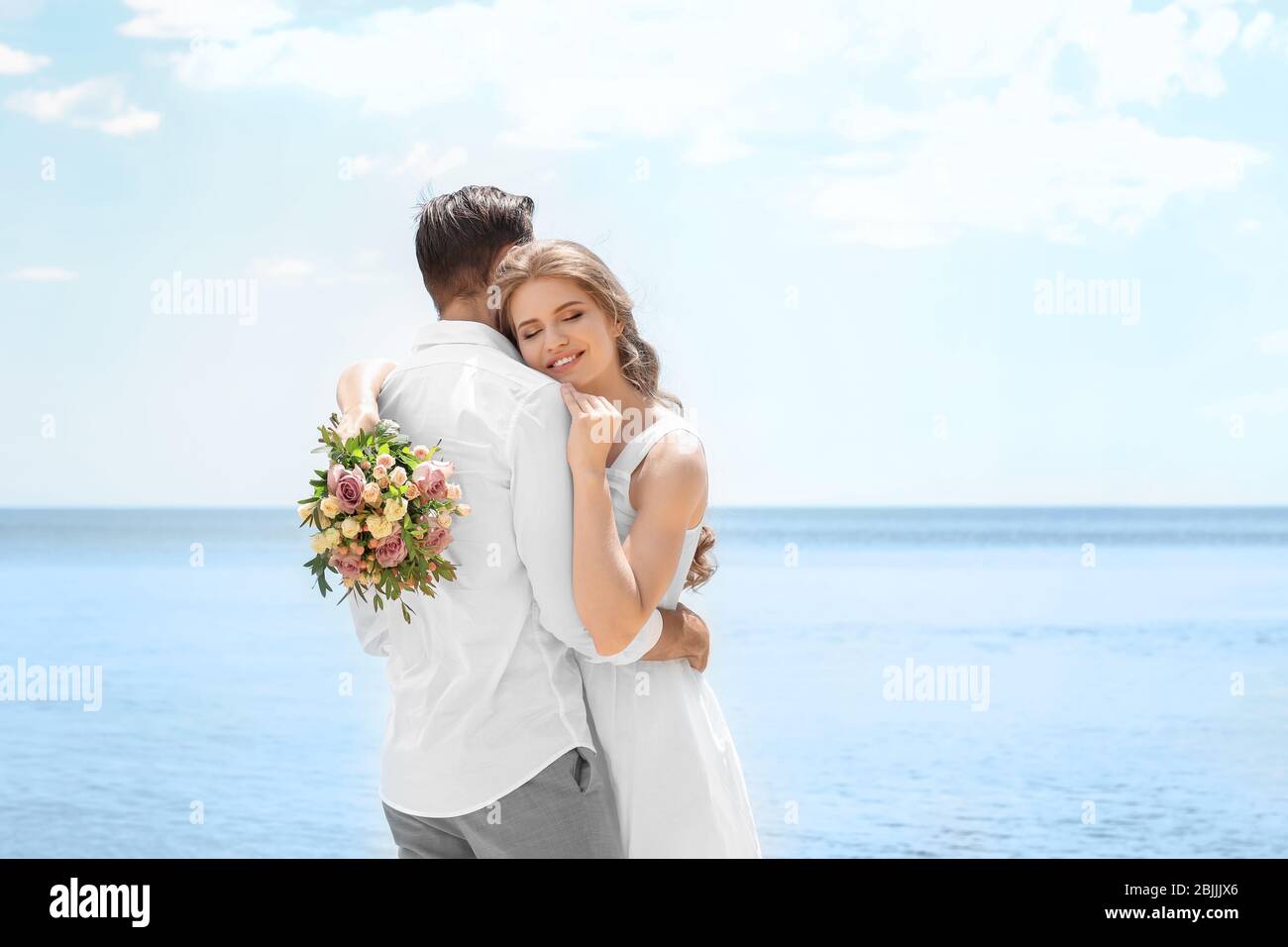 Happy newlywed couple hugging on seashore Stock Photo - Alamy