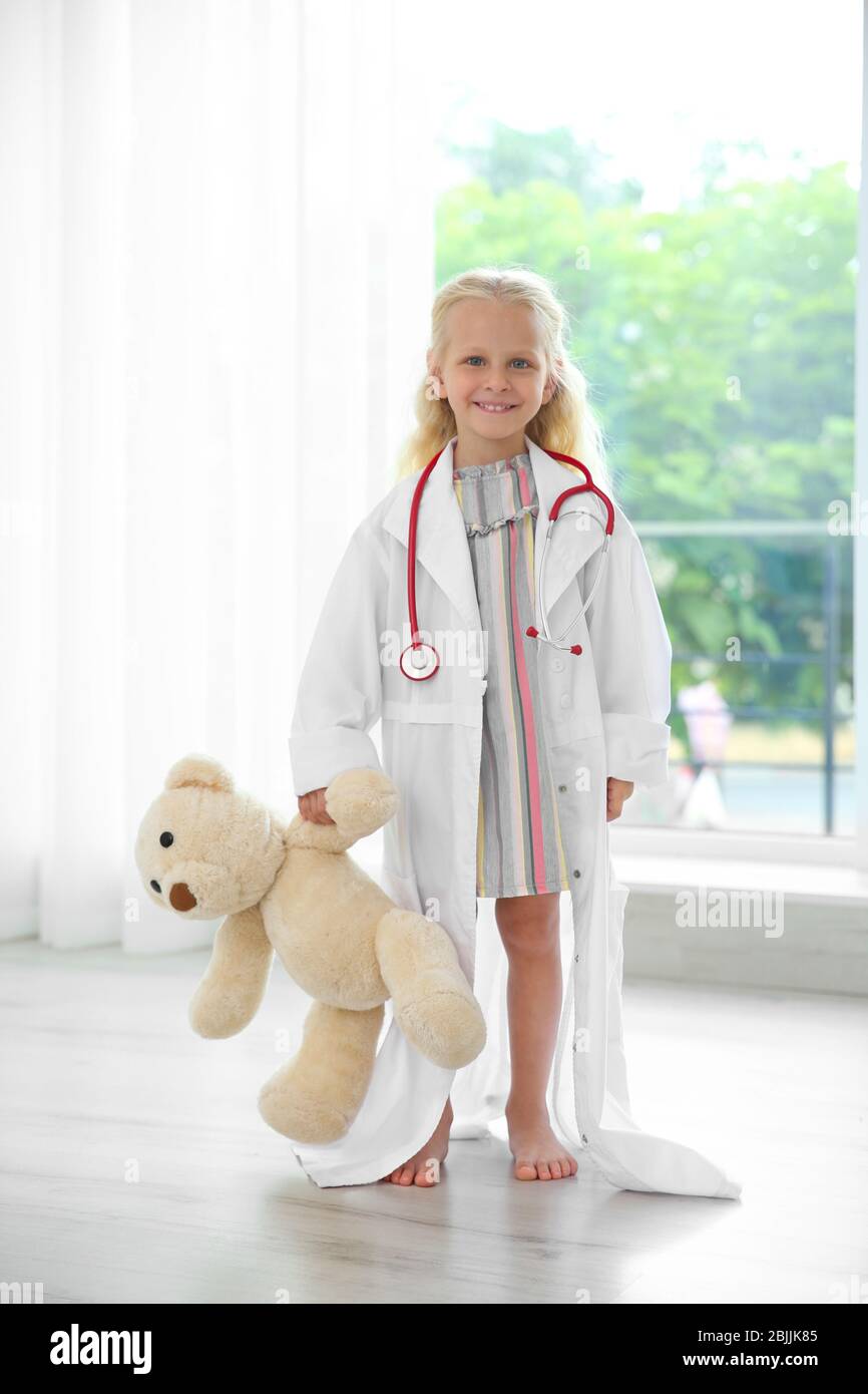 Little girl in medical coat with teddy bear standing near window Stock  Photo - Alamy
