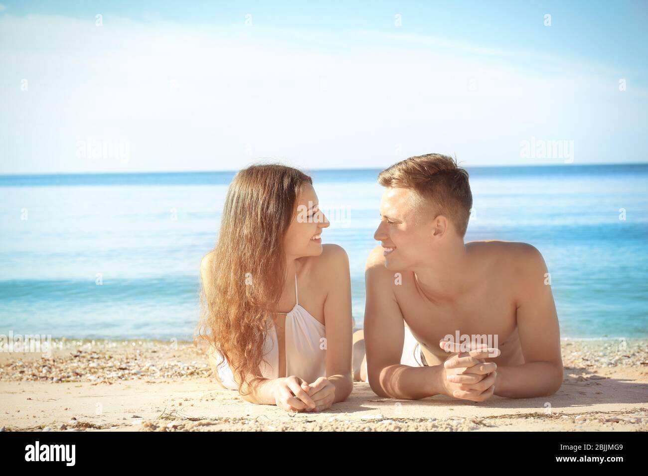 Happy young couple lying on sea beach at resort Stock Photo - Alamy