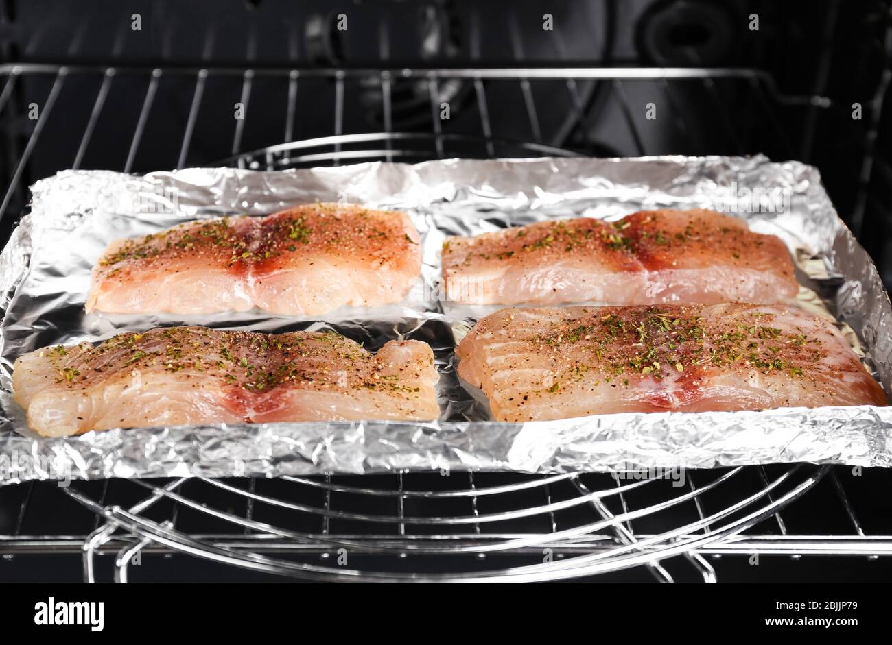 Raw fish fillets with spices in oven Stock Photo - Alamy
