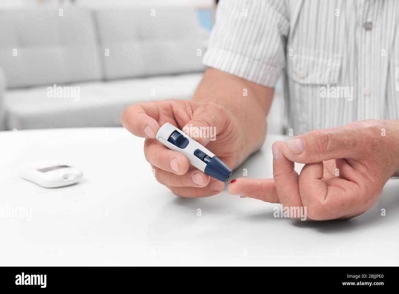 Man taking blood sample with lancet pen indoors Stock Photo Alamy