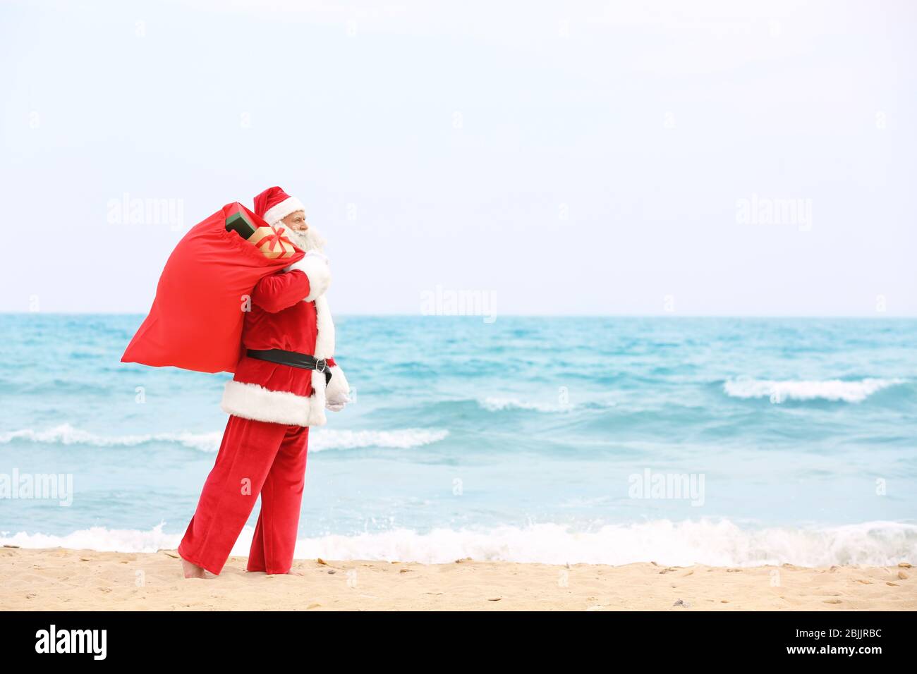 Authentic Santa Claus with big red bag full of gifts on beach Stock ...