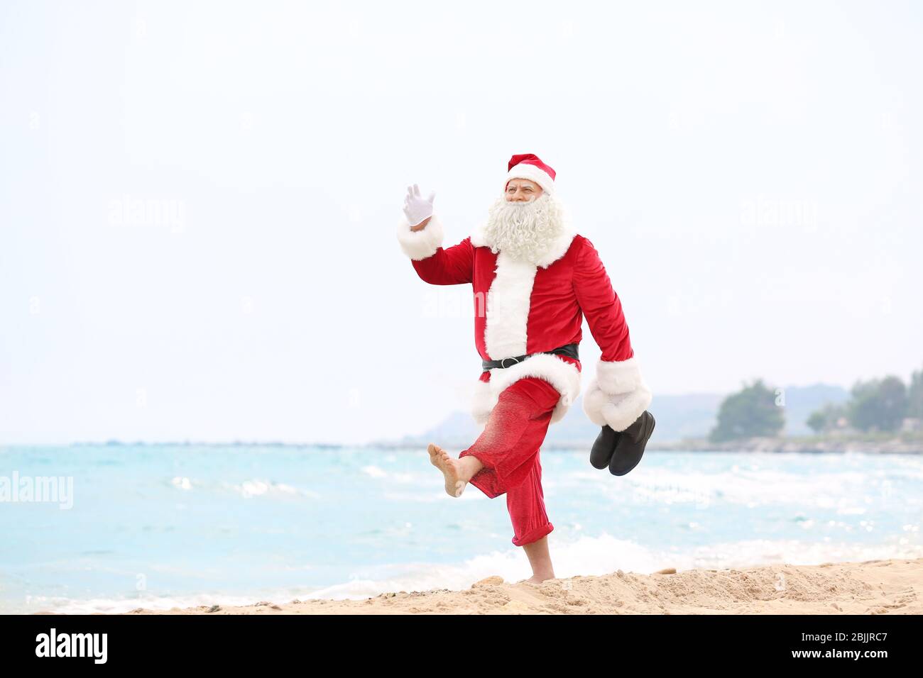 Authentic Santa Claus walking on beach Stock Photo