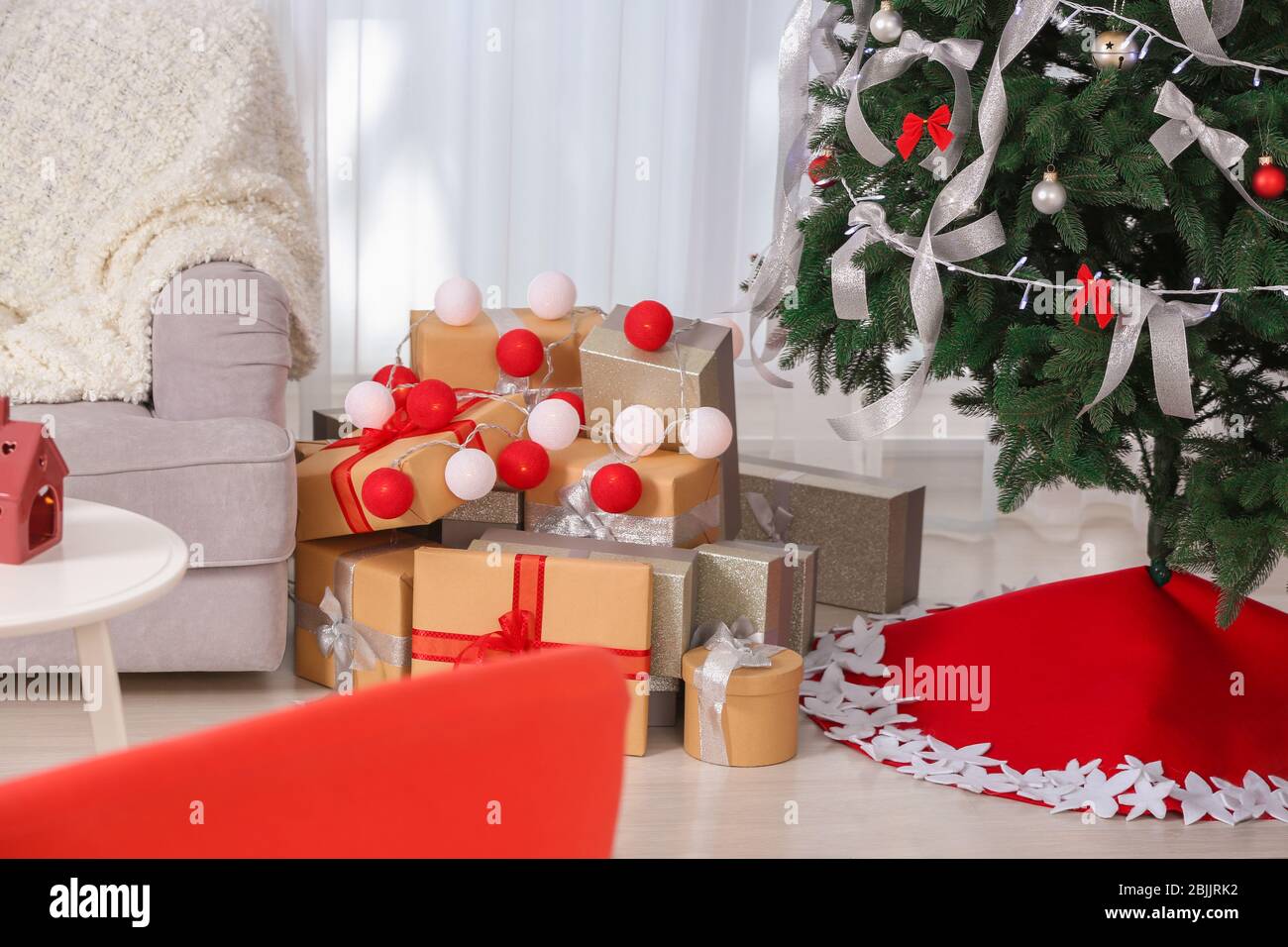 Beautiful Christmas tree with skirt and gifts at home Stock Photo - Alamy