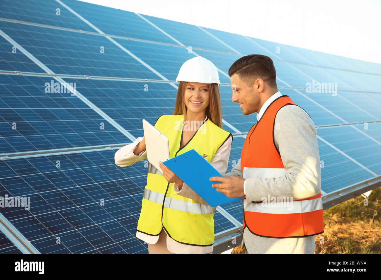 Engineers discussing project on installation of solar panels outdoors ...