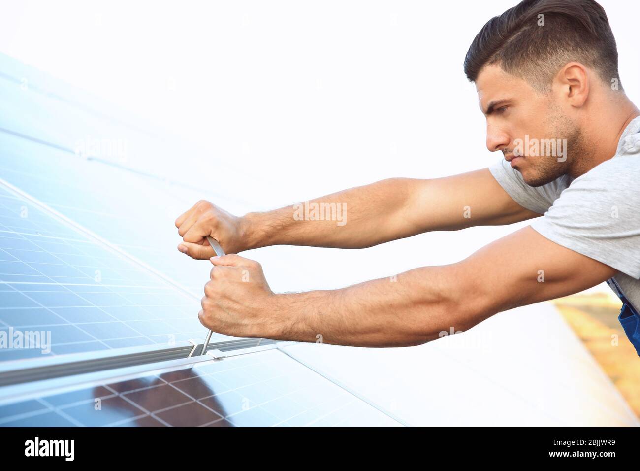 Young worker installing solar panels outdoors Stock Photo
