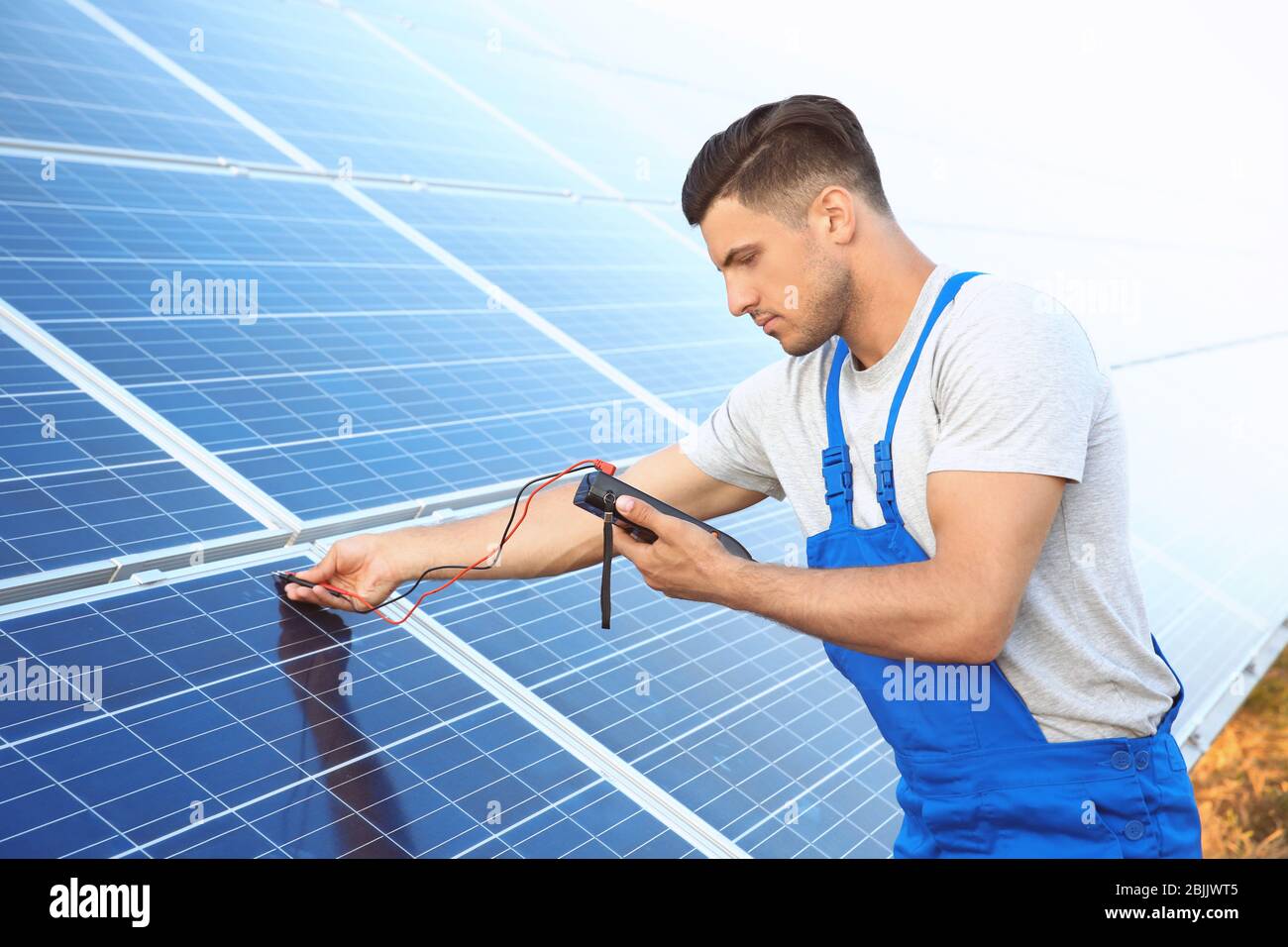 Using Multimeter On Solar Panel Young worker checking installation of solar panels by using multimeter ...