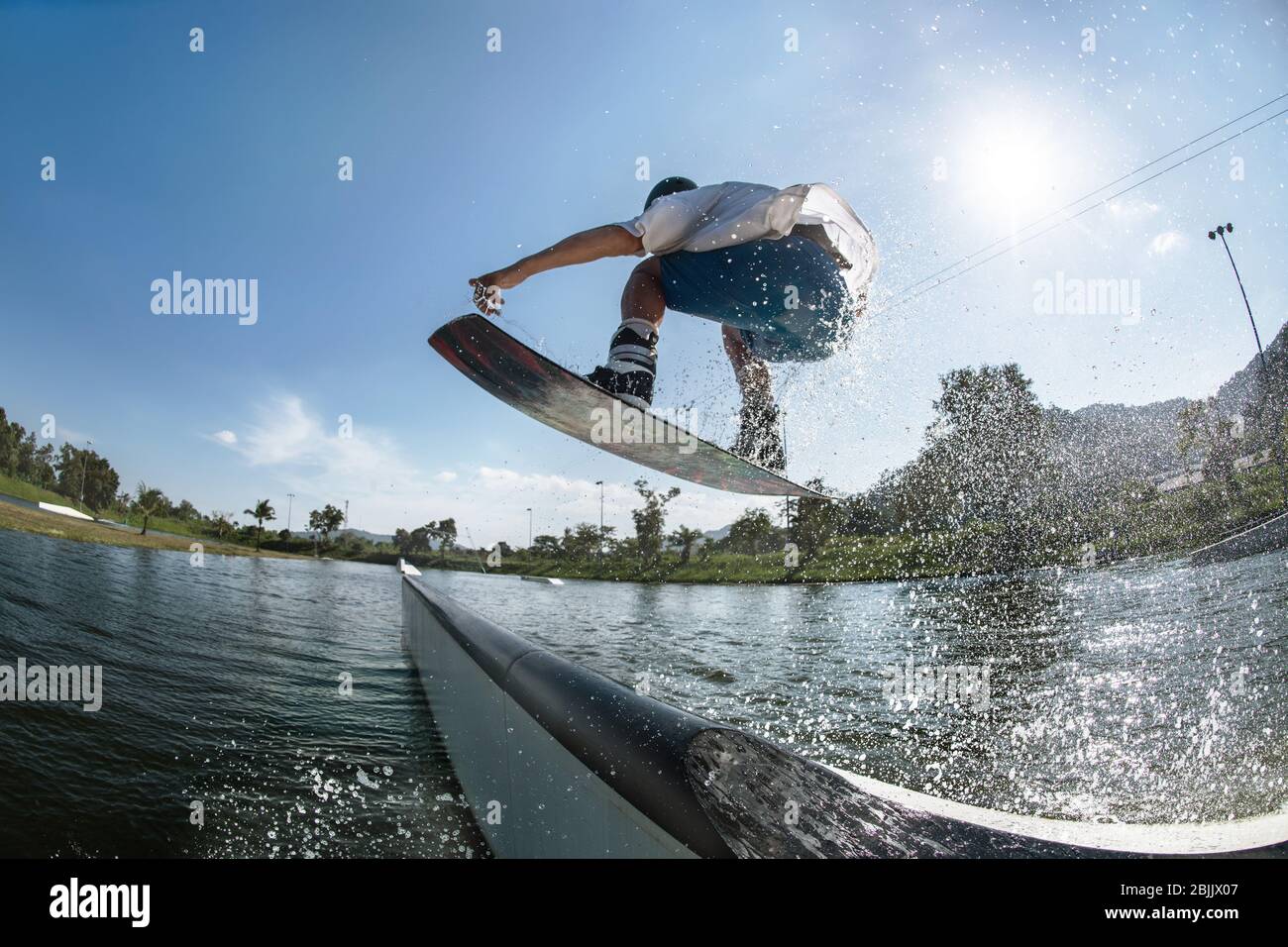Ma wakeboarder jumps at ramp at wake park Stock Photo