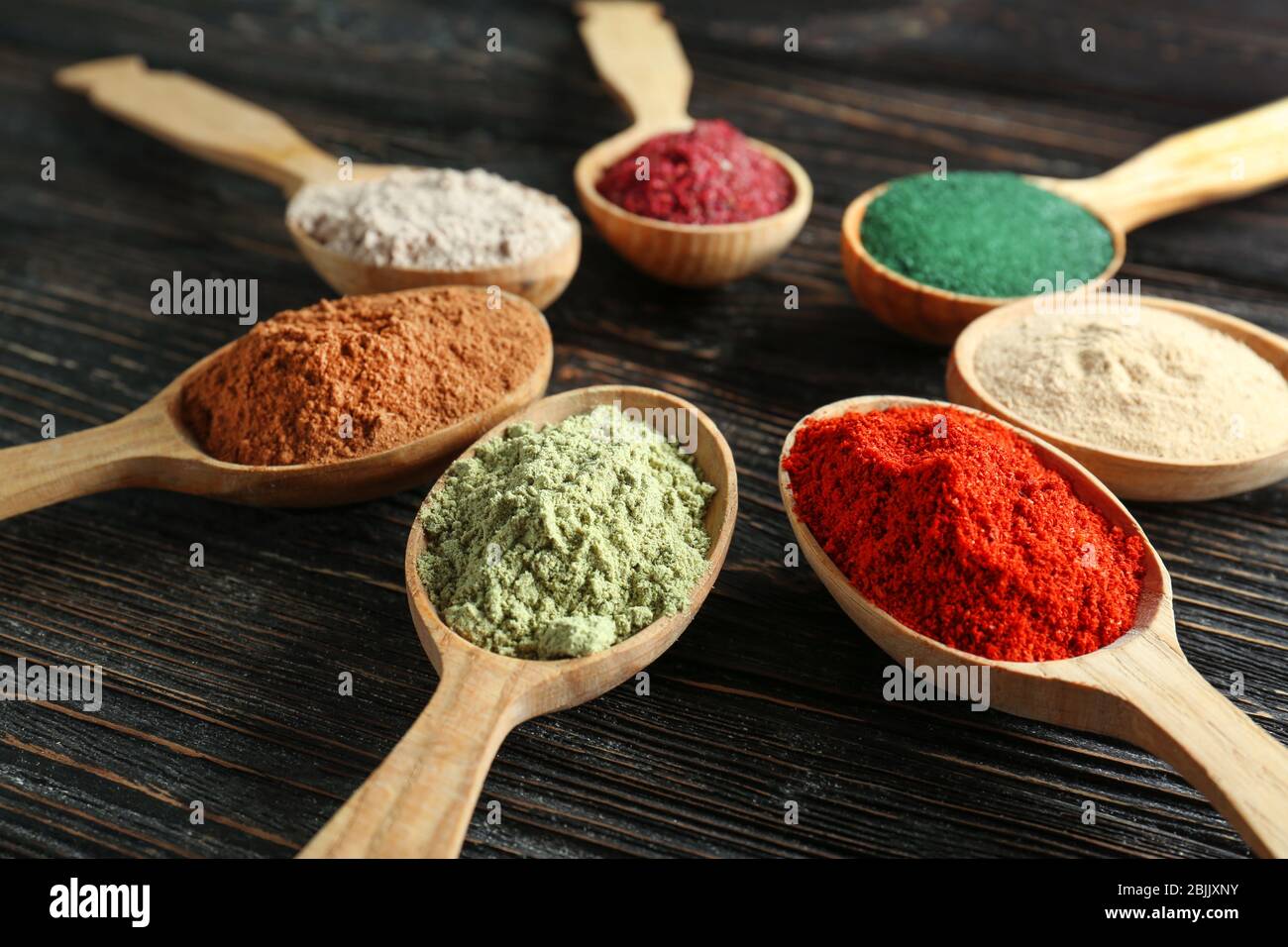Different colorful superfood powders in spoons on wooden table Stock ...