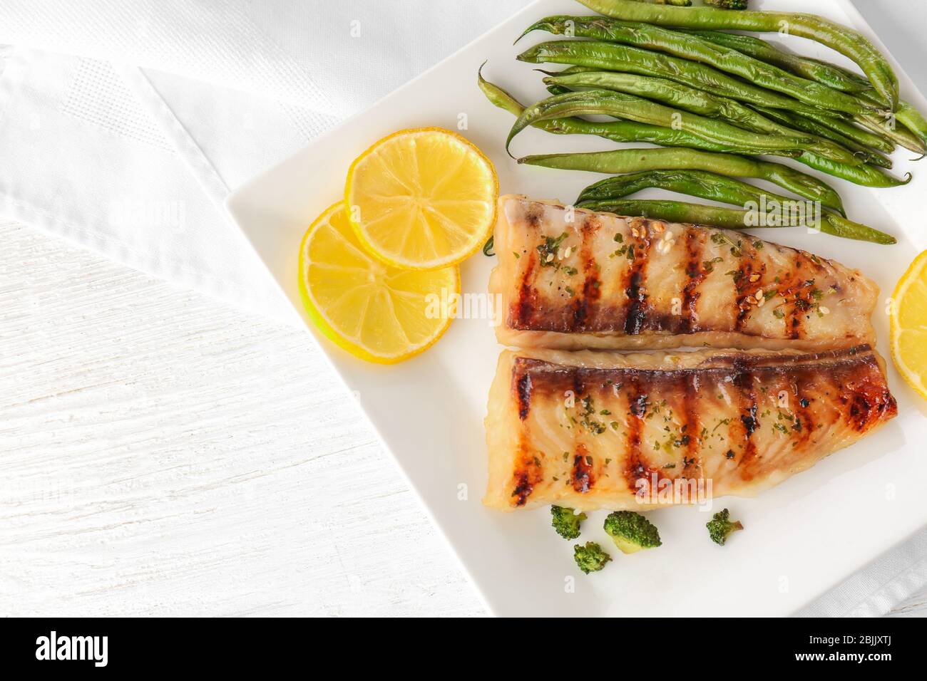 Plate with tasty fish and green beans on table Stock Photo - Alamy